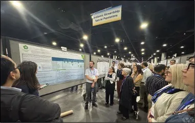 A group of conference attendees gathered around a research poster at IDWeek 2025, beneath a sign reading Antibiotic Stewardship: Special Populations.